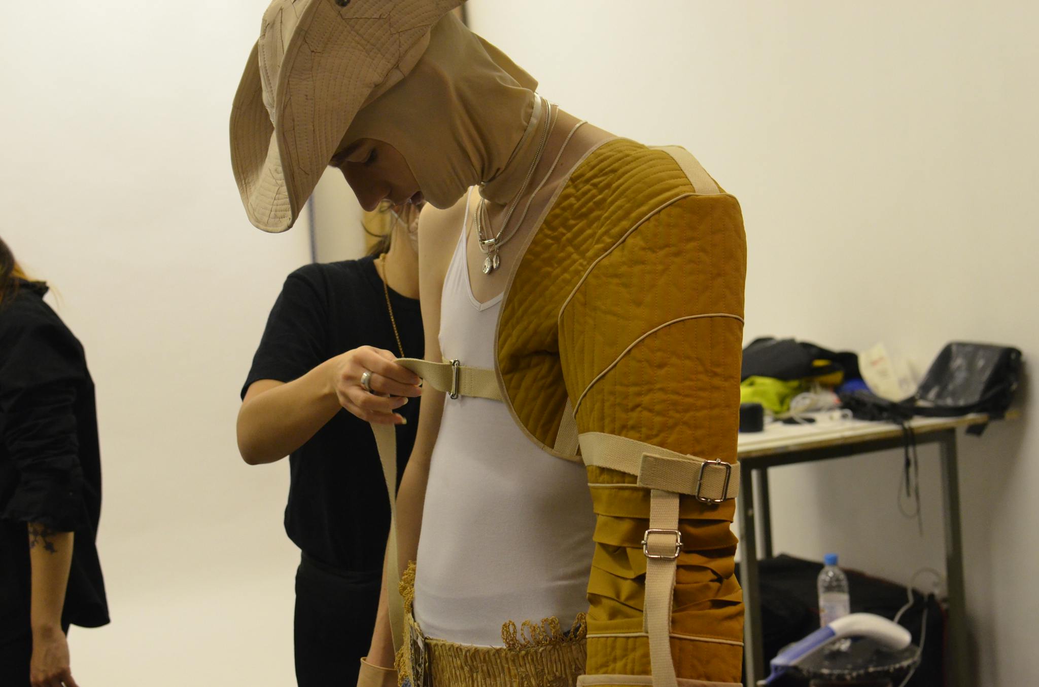 Anonymous female designer helping serious male model to wear unusual clothes before fashion shoot