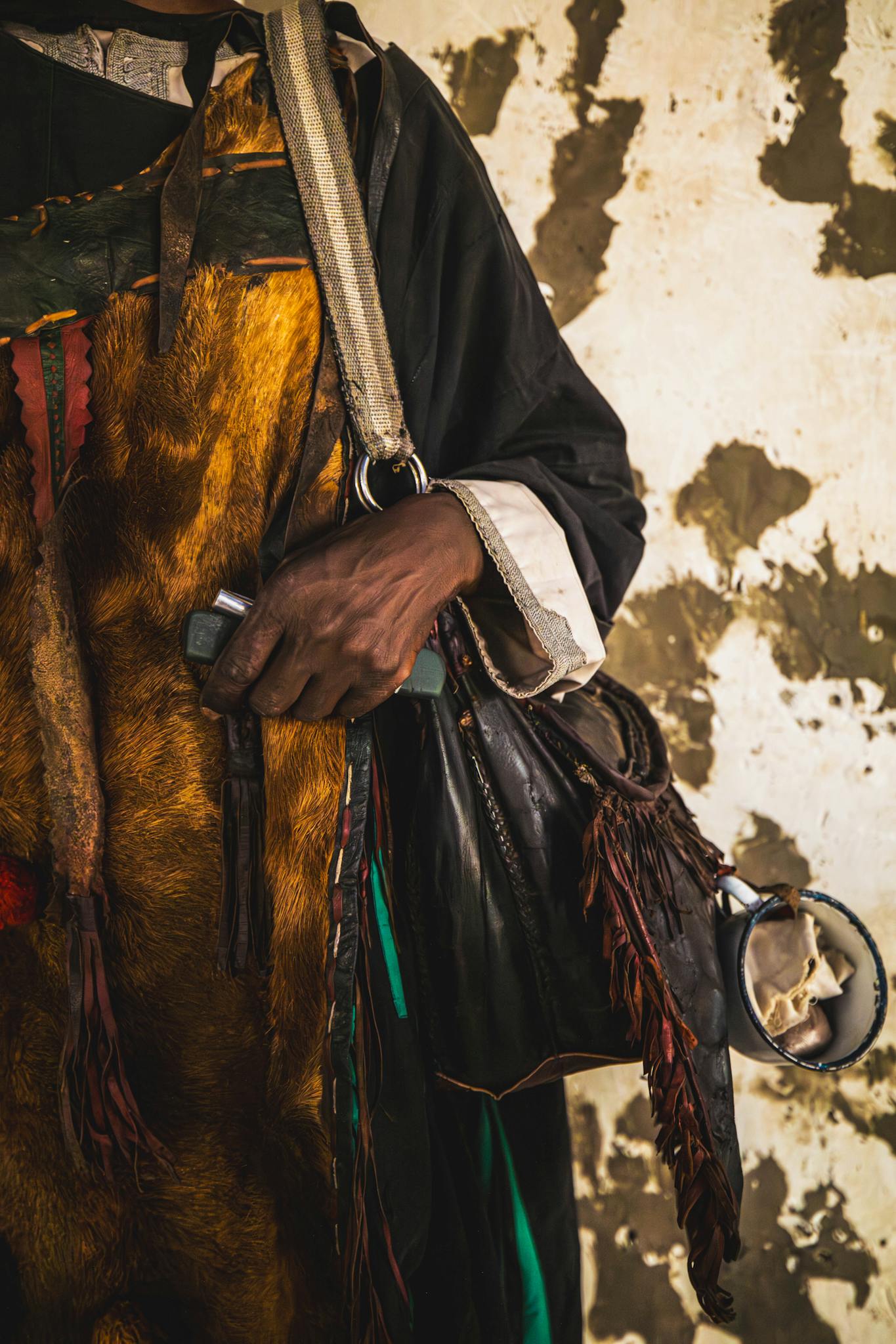 Close-up of traditional African attire featuring a handbag and tools, showcasing cultural craftsmanship.