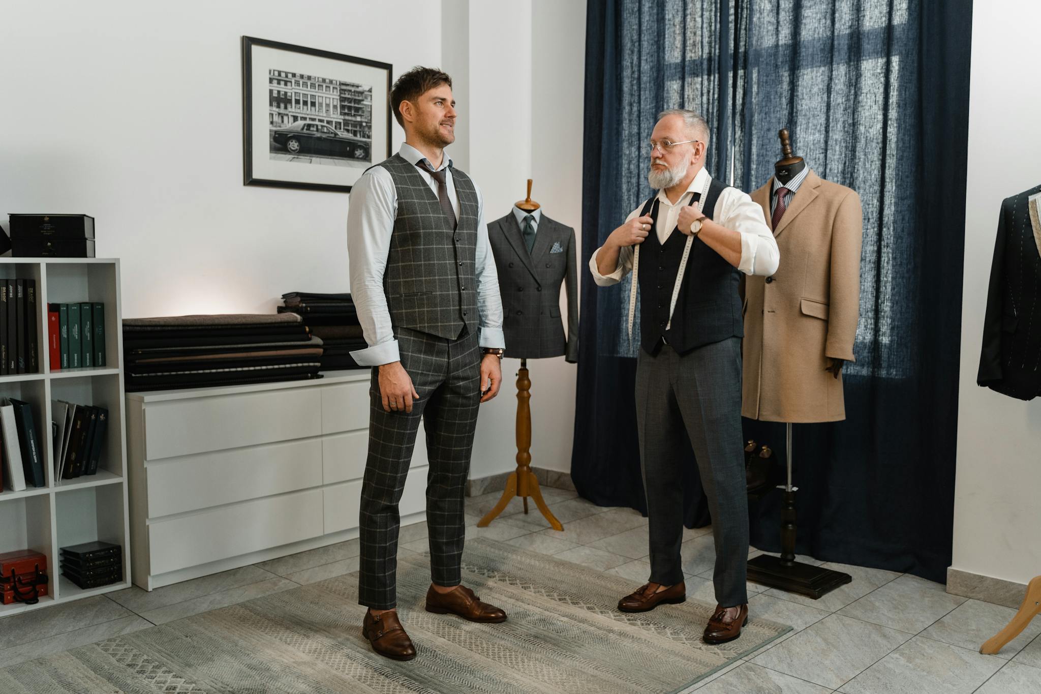 Two men in a fashion studio discussing suit designs, focusing on tailoring and style.